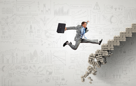Young businessman walking up collapsing staircase representing success conceptの写真素材
