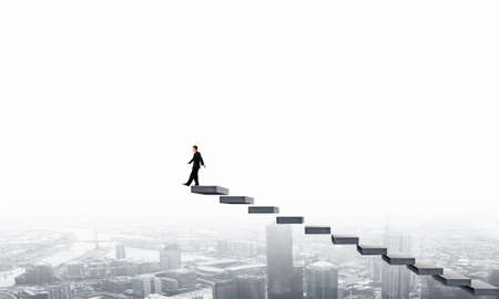 Young businessman walking up on staircase representing success conceptの写真素材