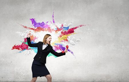Young businesswoman with red phone receiver in handsの写真素材