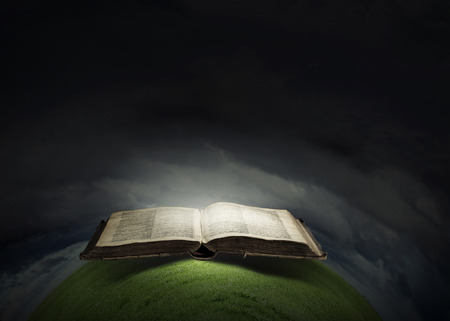 Opened book with light on pages on black backgroundの写真素材