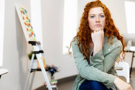 Young female artist in gallery with her pictureの写真素材