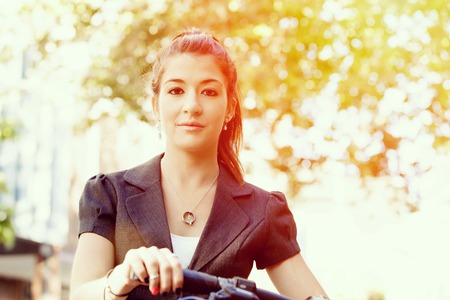 Young woman in business wear commuting on bicycle in cityの写真素材