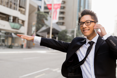 Businessman trying to catch a taxi in business cuty districtの写真素材