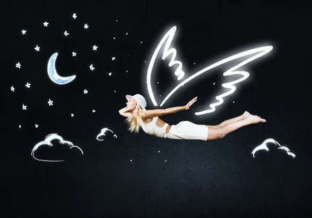 Cute girl with angel drawn wings on dark sky backgroundの写真素材