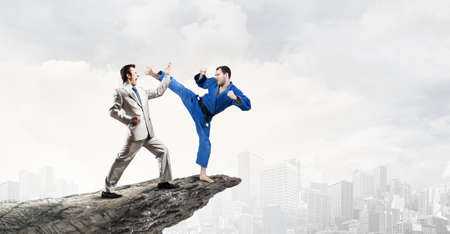 Young determined karate man fighting with businessman in suit