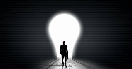 Back view of businessman looking at big glowing light bulbの写真素材