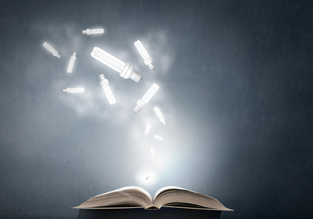 Opened book and glowing light bulbs flying from pagesの写真素材