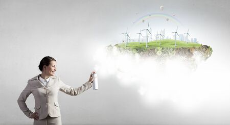 Young businesswoman spraying eco concept from aerosol balloonの写真素材