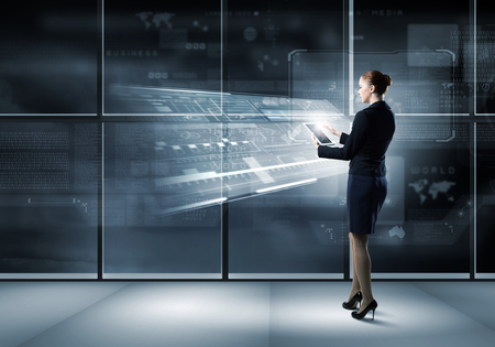 Full body of businesswoman with tablet pc against high tech backgroundの写真素材
