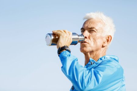 Handsome healthy man in sport wear drinking from sports bottleの写真素材