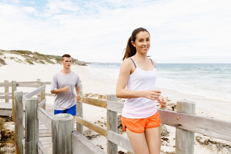 Runners. Young couple running on beach togetherの写真素材