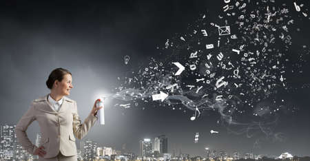 Young businesswoman spraying characters from aerosolの写真素材