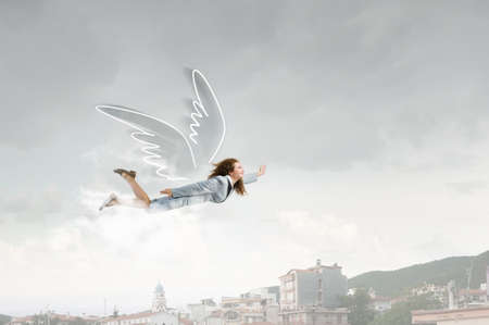 Young businesswoman with drawn wings flying high in sky