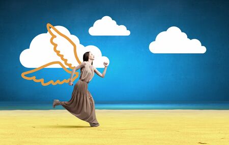 Attractive woman running with angel wings behind backの写真素材