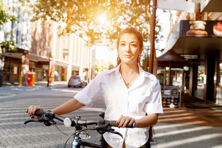 Portrait of happy young female bicyclist riding in cityの写真素材