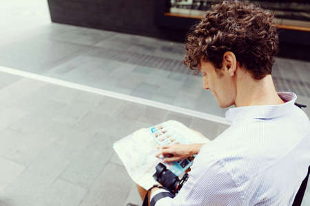 Young male tourist in city with camera and mapの写真素材