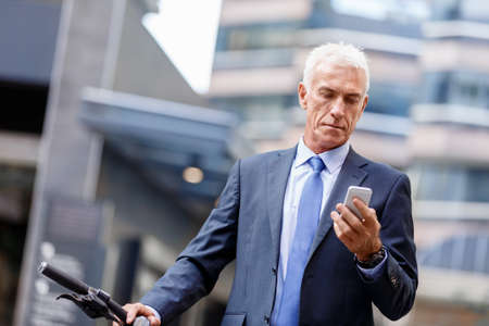 Portrait of confident businessman with his mobile phone outdoorsの写真素材