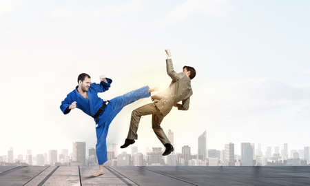 Young determined karate man fighting with businessman in suit