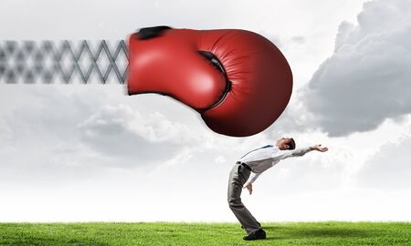 Young determined businessman fighting boxing glove on springの写真素材