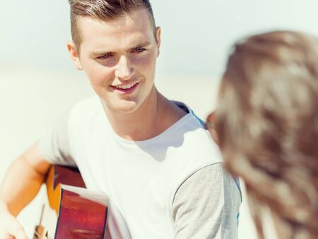 Picture of young smiling man playing guitar on beachの写真素材