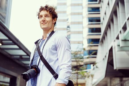 Happy male tourist in city walking with camera