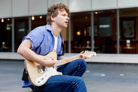 Portrait of young musician with guitar in city