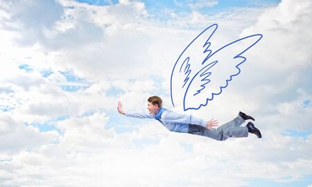 Young businessman with drawn wings flying in skyの写真素材