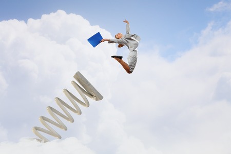 Businesswoman jumping on springboard as progress conceptの写真素材