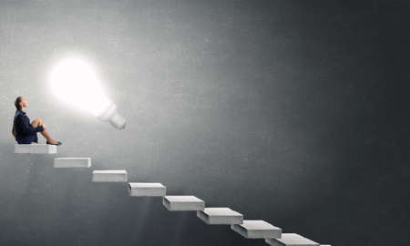 Bored young businesswoman sitting alone on ladder stepsの写真素材