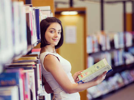 Happy young female student sudying at the library