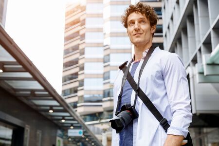 Happy male tourist in casual clothes in city with cameraの写真素材