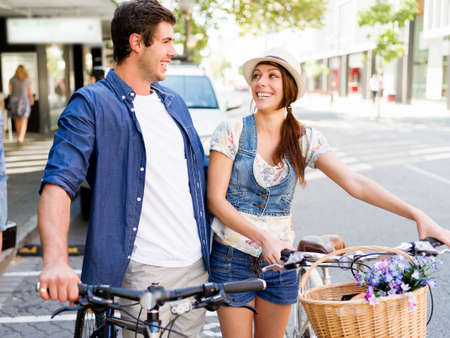 Happy young couple in city with bikeの写真素材