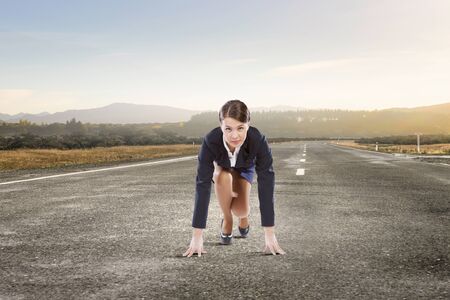 Young determined businesswoman standing in start position ready to competeの写真素材