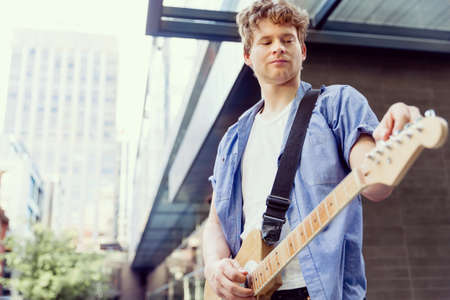 Portrait of young musician with guitar in city