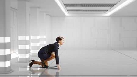 Young determined businesswoman standing in start position ready to competeの写真素材