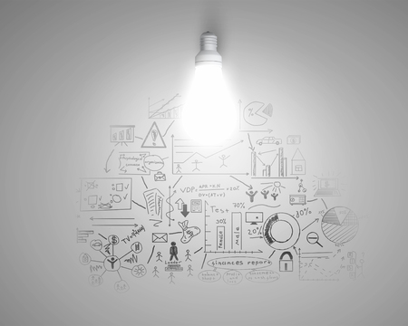 Glass glowing light bulb and business sketched ideasの写真素材