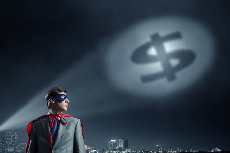 Young confident super businessman in mask and cape at nightの写真素材