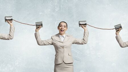 Young pretty businesswoman attaching tin phone to ear