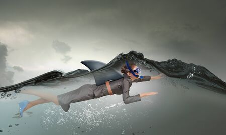 Young businesswoman with shark flipper swiming under waterの写真素材