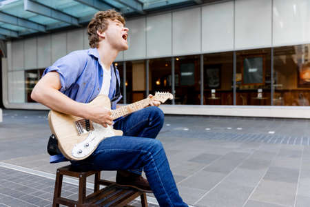 Portrait of young musician with guitar in cityの写真素材
