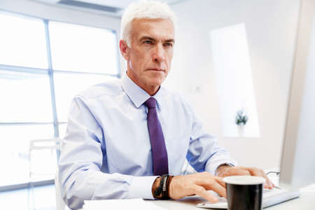 Businessman sitting in office working with computerの写真素材