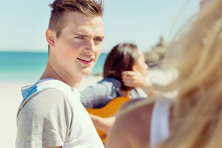 Portrait of young man on beach with his friends on backgroundの写真素材