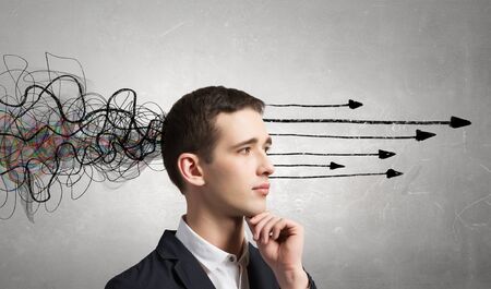 Thoughtful businessman with arrows and thoughts coming out of his headの写真素材