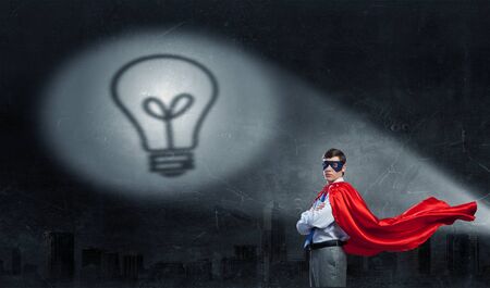 Young confident super businessman in mask and cape at nightの写真素材