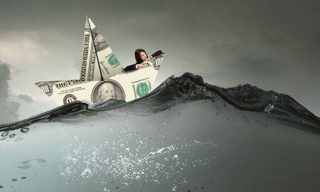 Successful businesswoman sailing on dollar boat in financial seaの写真素材