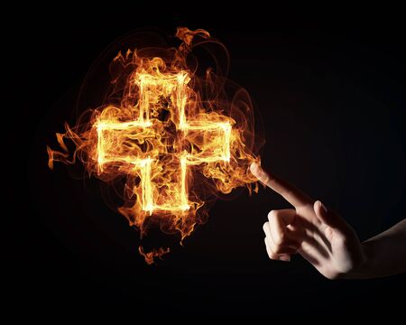 Finger touch glowing light cross sign on dark backgroundの写真素材