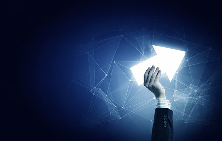 Businessman on dark background taking with fingers arrow icon
