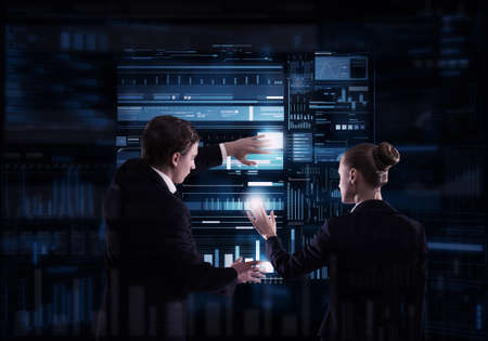 Rear view of businessman and businesswoman working with virtual panel interface