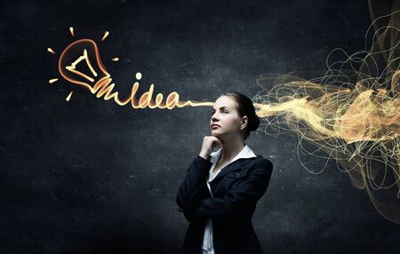 Young pensive businesswoman and ideas coming out of her headの写真素材