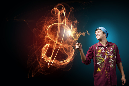 Guy painter drawing dollar sign on dark backgroundの写真素材